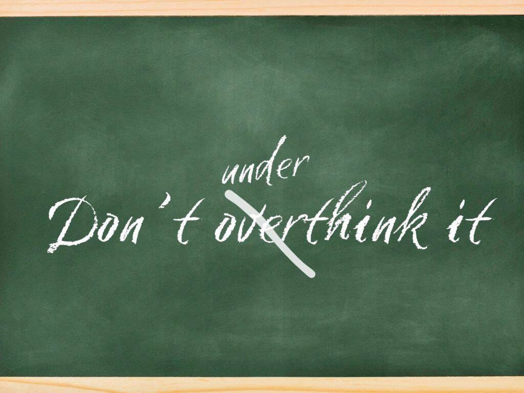 A chalkboard has written on it "don't overthink it" and "over" is stroked out with "under" written above it.